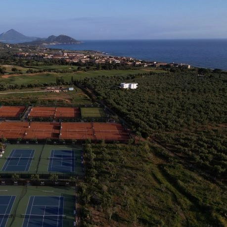 Aerial view of tennis courts near the coastline surrounded by nature.